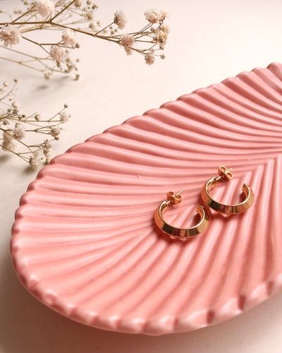 粉色和白色条纹织物上的金银戒指